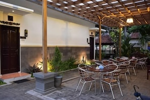 Un patio exterior con pérgola, zona de estar y una puerta.
