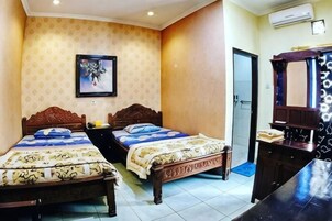 Habitación de hotel con dos camas, un aparador de madera, un espejo y un cuadro en la pared.
