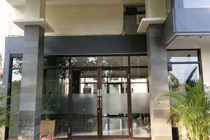 Entrada de un edificio con puerta de vidrio y un pilar de concreto.
