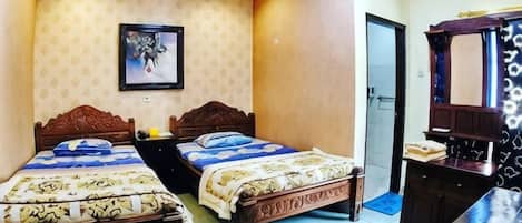 A hotel room with two beds, a desk, a mirror, and an air conditioning unit.