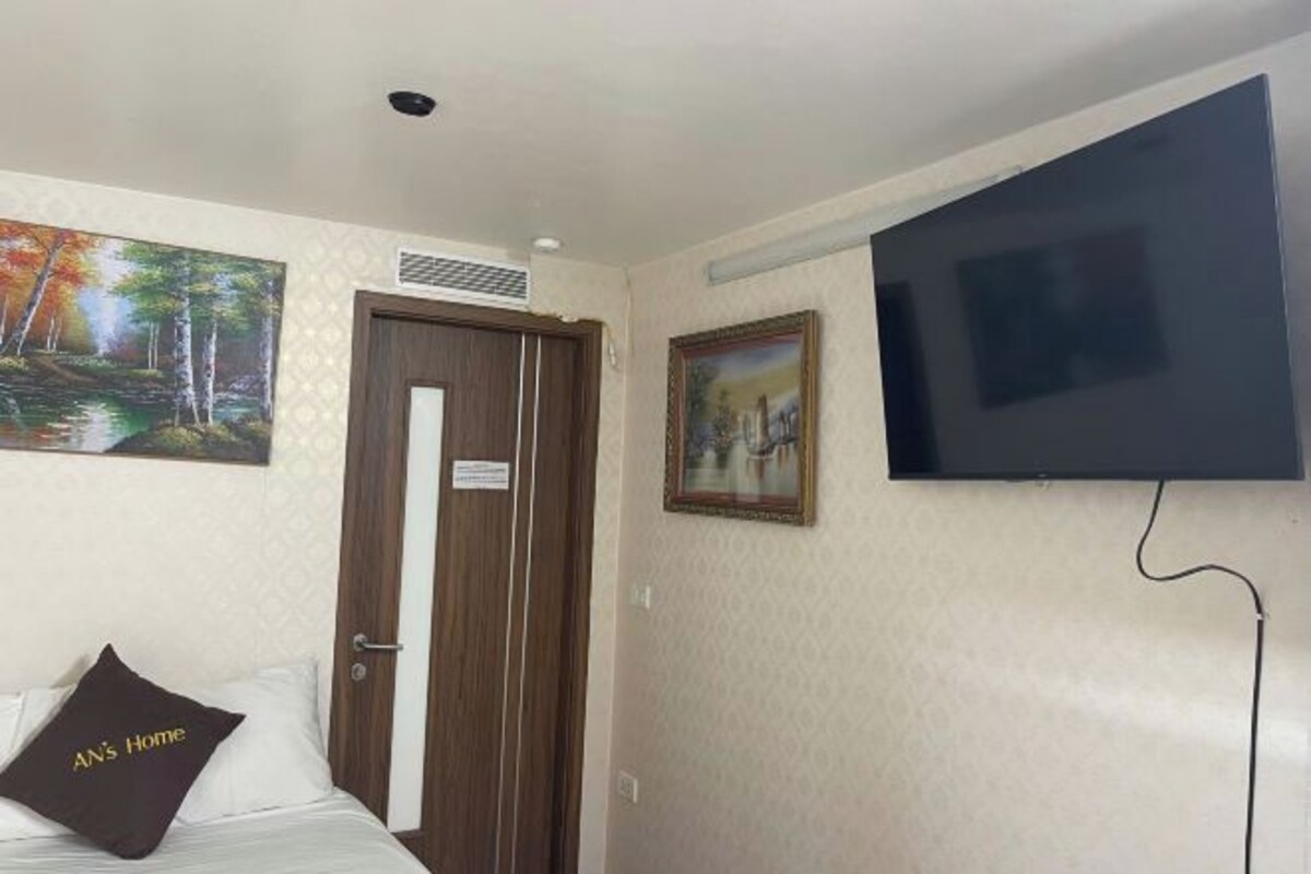 A hotel room with a bed, a TV mounted on the wall, and two paintings.