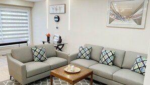 Un salon moderne avec un canapé d’angle, une table basse et un tapis à motifs.