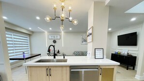 Une cuisine moderne dotée d’un îlot central, d’appareils électroménagers en acier inoxydable et d’un lustre.