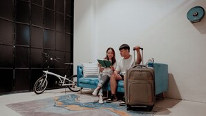 A room with a blue sofa, a white bicycle, and a suitcase. - Code Hostel at Lavender (Singapore)