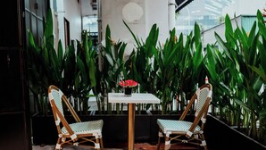 A small outdoor seating area with two wicker chairs and a table, surrounded by lush green plants. - Code Hostel at Lavender (Singapore)