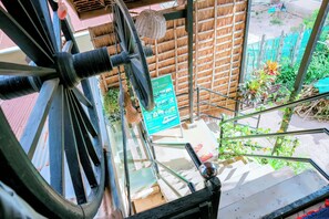 A view from a window overlooking a staircase and a thatched-roof structure. - Old Khmer House (Siem Reap)