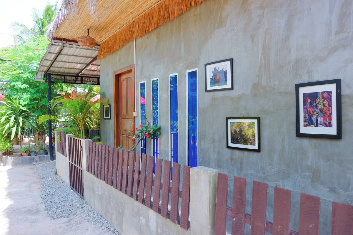 Un bâtiment doté d’un toit de chaume, d’une porte en bois et d’un mur orné de tableaux encadrés.
