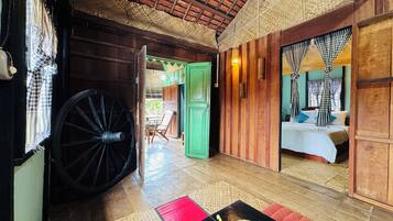 Una habitación de madera tradicional con un gran carrusel, una cama con cortinas de cuadros y una puerta verde que da a otra habitación.