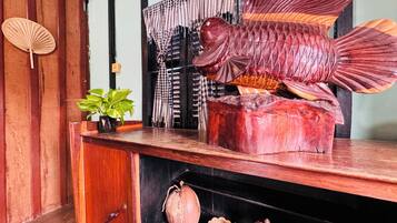 A wooden fish sculpture on a shelf, a potted plant, and a traditional Japanese fan.