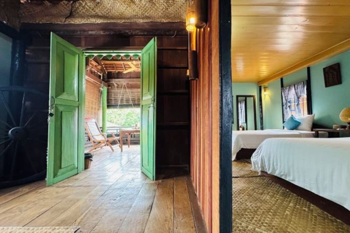 Una habitación con una cama, una silla y una puerta abierta que da a un espacio exterior.