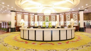 A hotel lobby with a central reception desk, decorative panels, and a chandelier. - Doson Resort (Hai Phong)