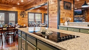 A wooden interior with a kitchen island, dining area, and large windows. - Sleeps 32: Perfectly Designed For Groups/Reunions! (Gatlinburg)