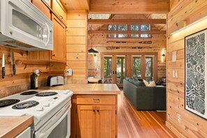 A compact kitchen with a microwave, stove, and wooden cabinets.