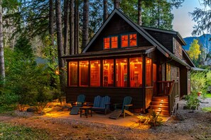 A cabin with a large front porch, multiple windows, and a staircase leading to the entrance.