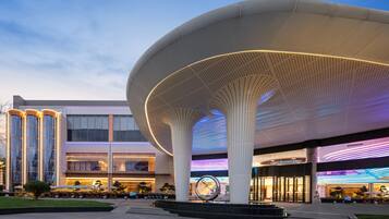 Un bâtiment moderne, avec une grande structure de toit ajouré, blanche, qui se trouve au premier plan.