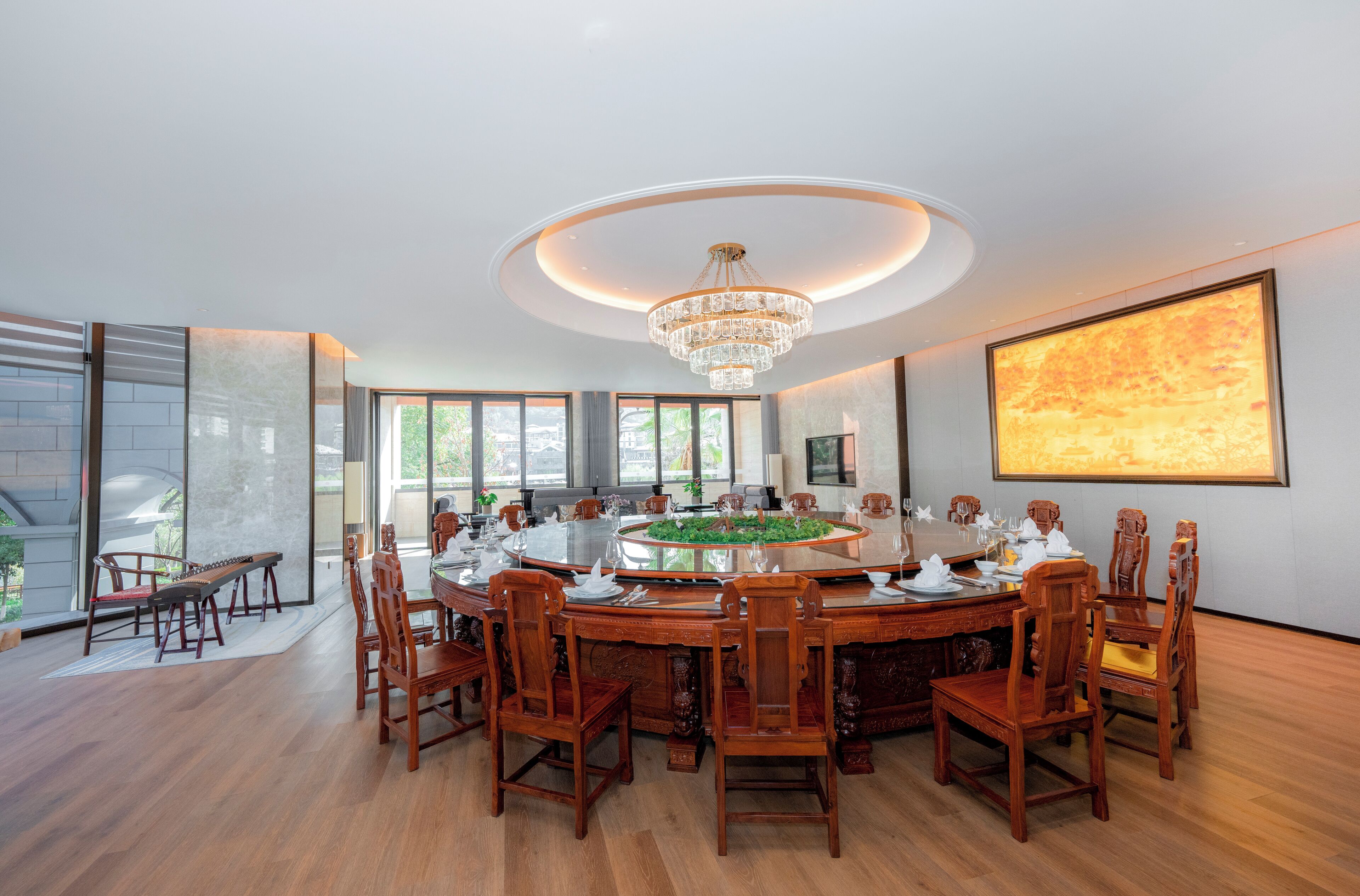 Uma sala de jantar ampla com uma mesa redonda, cadeiras de madeira e um candelabro.
