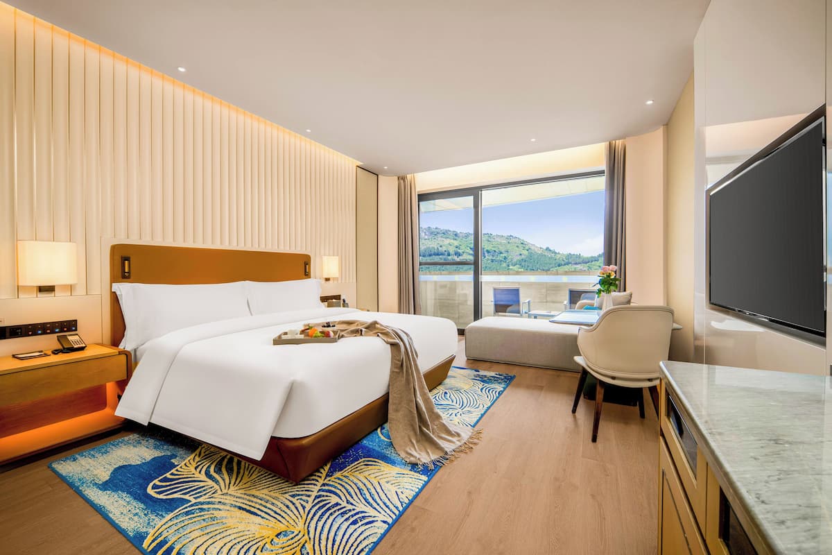 Une chambre d’hôtel avec un grand lit, un bureau, une télévision et une vue sur l’extérieur.