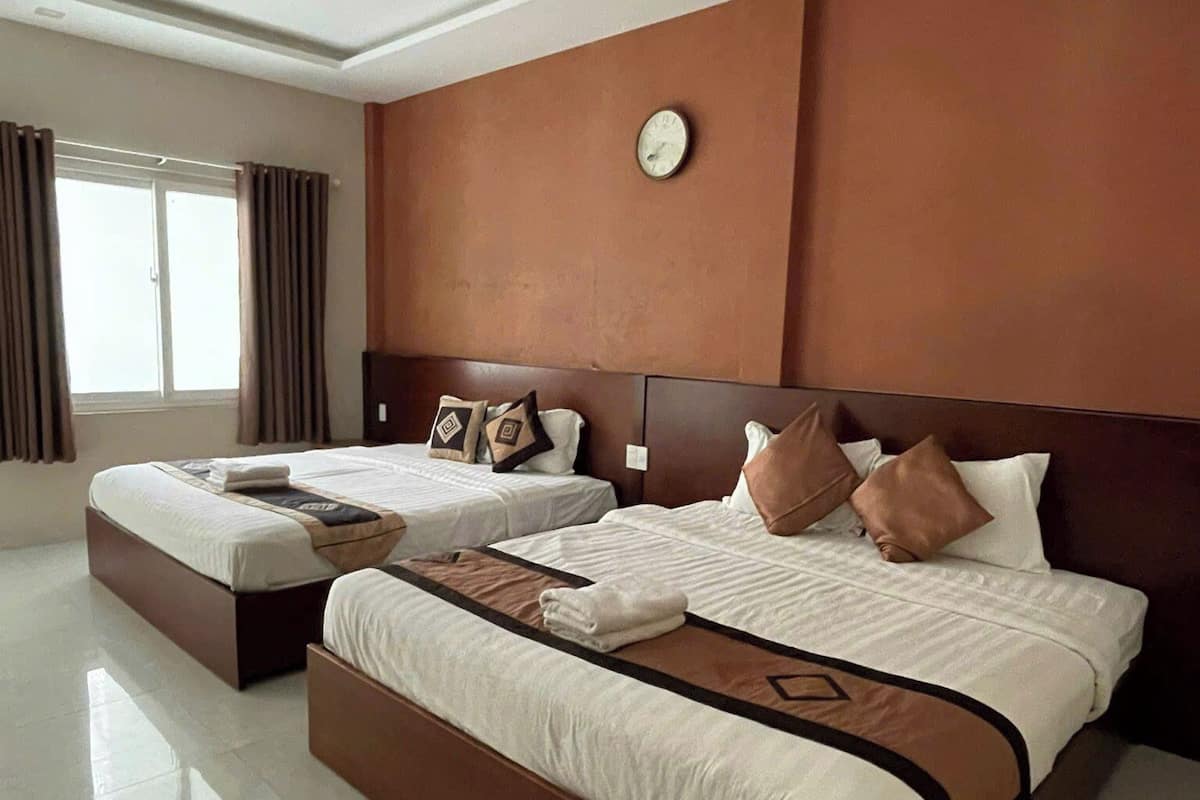 A large, modern hotel room with a large bed, a smaller bed, and a separate seating area.