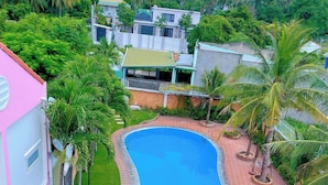 A swimming pool with a curved design, surrounded by a brick pathway and palm trees. - Volga Hotel & Appartment Mui Ne (Mui Ne)