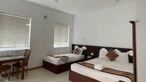 A modern hotel room with a dining area, two single beds, a desk, and a large window. - Volga Hotel & Appartment Mui Ne (Mui Ne)
