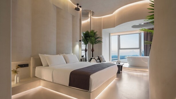 A modern bedroom with a large bed, a bathtub, and a view of the city. - Ziggy Hotel (Changsha)