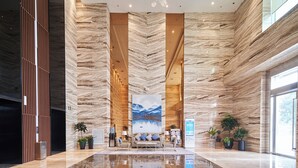 A spacious lobby with a large seating area, a prominent artwork on the wall, and a modern chandelier. - Ziggy Hotel (Changsha)