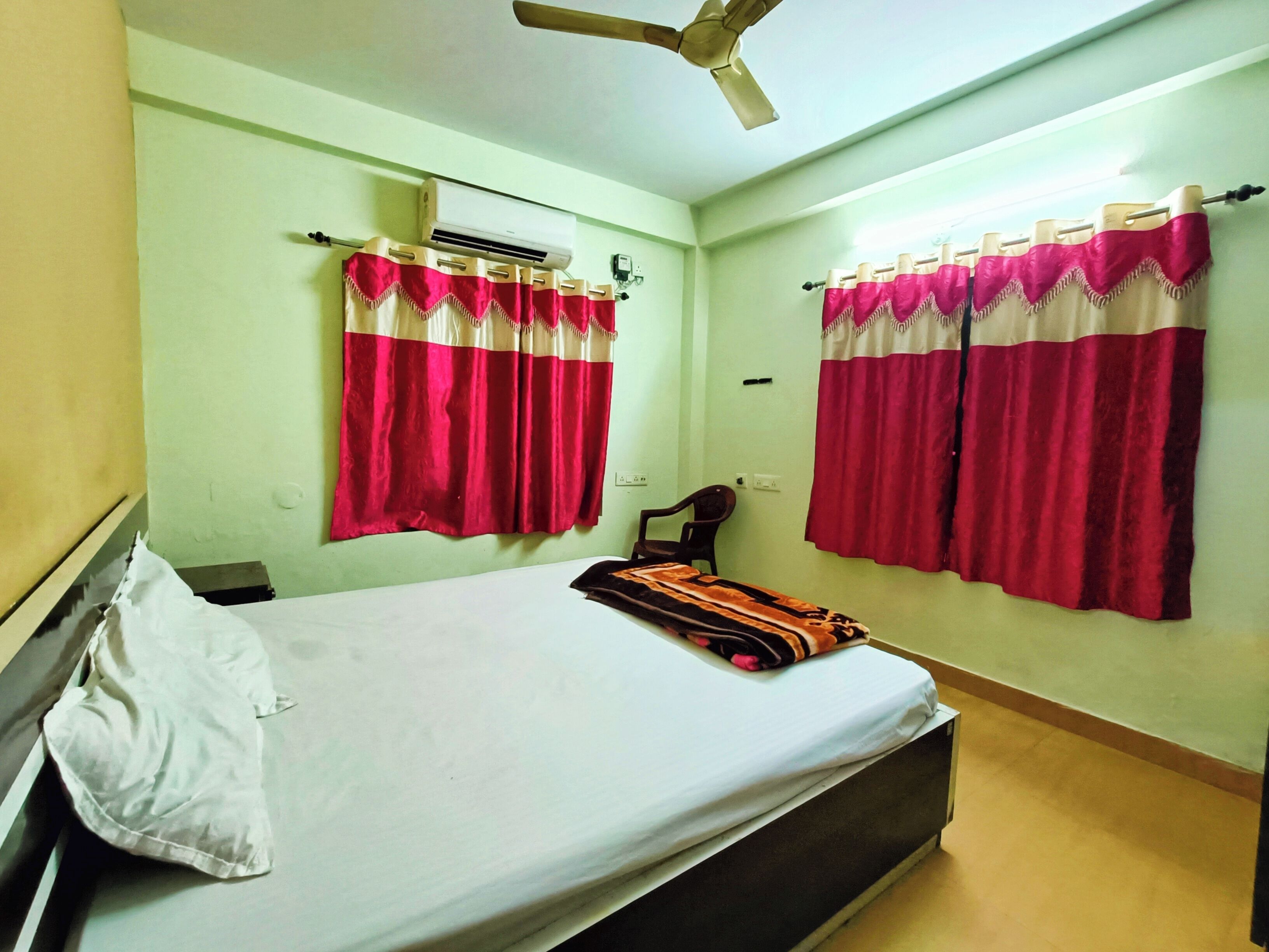 Un dormitorio con una cama, dos equipos de aire acondicionado y cortinas.