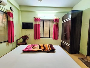 Una habitación con cama, una silla, un televisor y un armario.