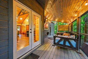 A wooden cabin with a porch, a swing, and a dining area. - Silver Linings · Honeymoon Cove: Daybed + Fire Pit Swings & Hot Tub (Broken Bow)