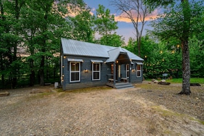 Une cabane rustique avec un toit en métal, un revêtement en bois et une véranda dotée de bancs.