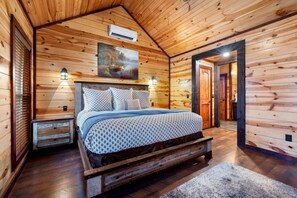 Une chambre dans une cabane en bois, avec un lit, des tables de chevet et un tableau accroché au mur.