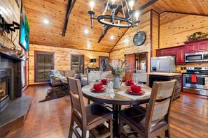 L’intérieur chaleureux d’un chalet en bois comprend un coin repas, une cuisine et une cheminée.