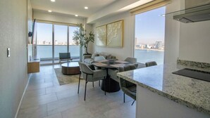 A modern kitchen with a granite countertop, a dining area with a round table and chairs, and a balcony with a view of the city.