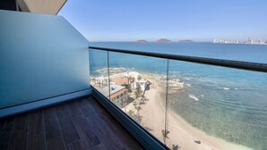 A balcony with a clear view of a beach and the ocean.