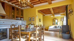 Un'ampia cucina con mobili in legno, un tavolo da pranzo con sedie e un lampadario importante. C'è un'accogliente zona living con un divano e un caminetto.