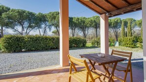 Zona relax all'aperto con tavolo e sedie, circondata da ghiaia e piante.