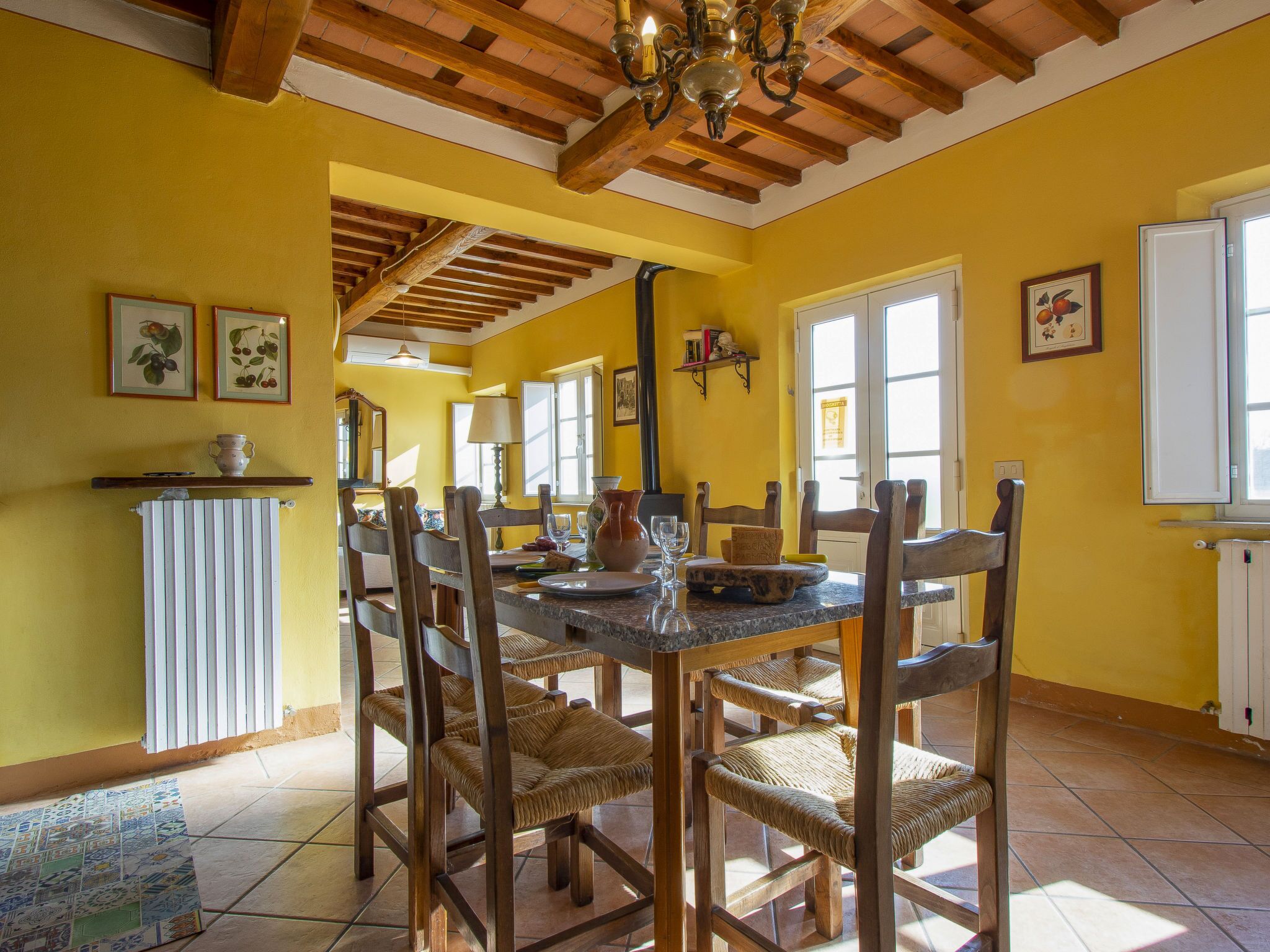 A dining area with a wooden table and chairs, yellow walls, and a tiled floor.