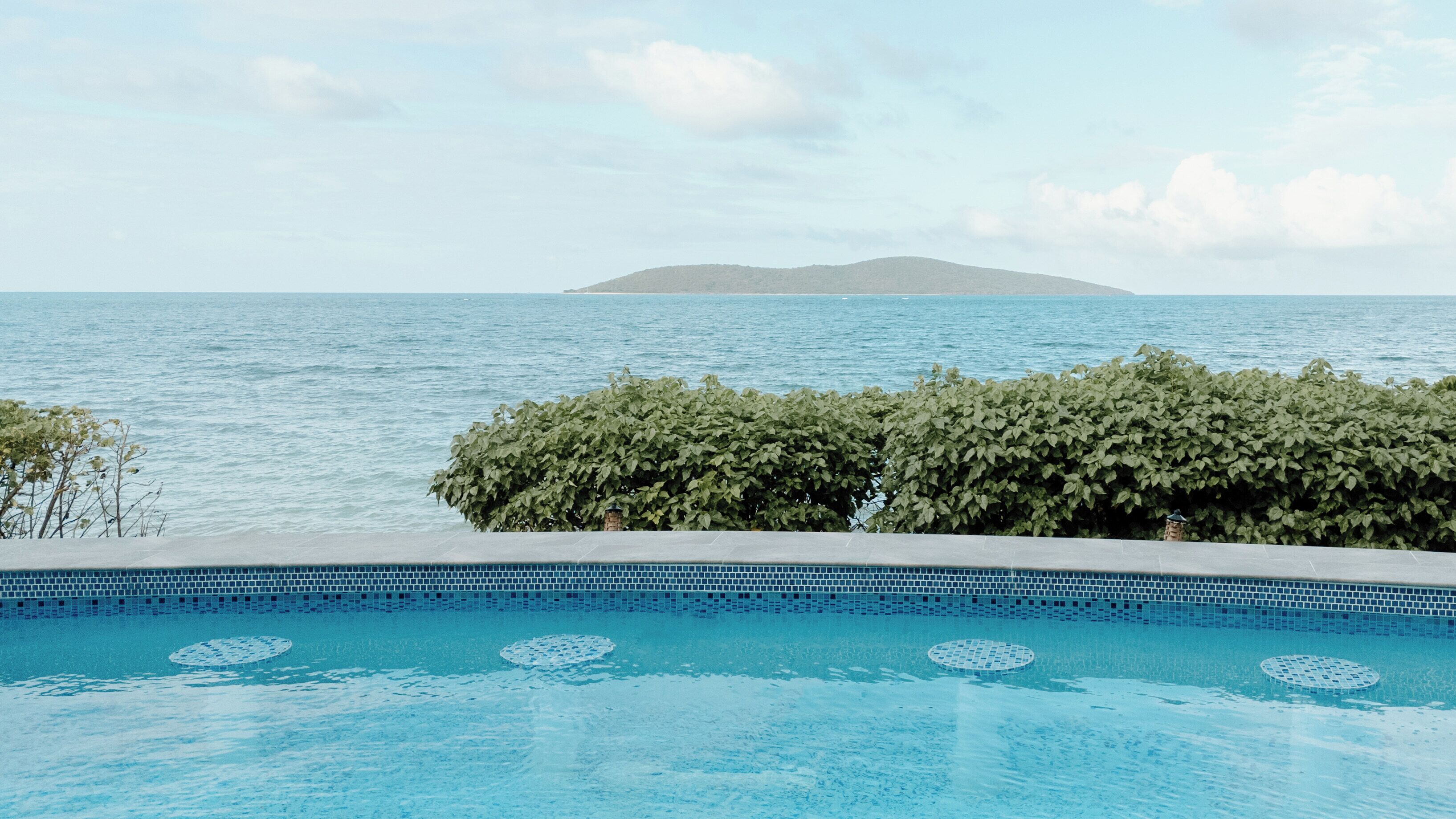En swimmingpool med utsikt över havet och en avlägsen ö.