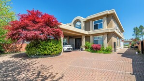 A two-story building with a car parked in front, surrounded by greenery and a clear blue sky. - Amy Guesthouse (Richmond)