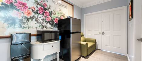 A kitchen with a refrigerator, microwave, and water dispenser.