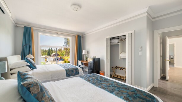 A hotel room with two beds, a desk, a TV, and a closet. - Amy Guesthouse (Richmond)