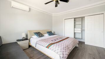 Un dormitorio con cama, mesita de noche, lámpara y ventilador de techo.