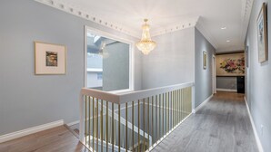 A modern interior with a staircase, a chandelier, and framed artwork on the walls. - Amy Guesthouse (Richmond)