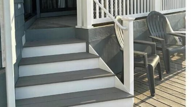 Una terraza de madera con una escalera que lleva a un porche cubierto.