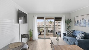 A modern apartment with a dining area, a sofa, and a balcony with a city view. - Just Beachy (Corpus Christi)