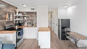 A modern kitchen with white cabinetry, a wooden countertop, and a built-in oven. - Just Beachy (Corpus Christi)