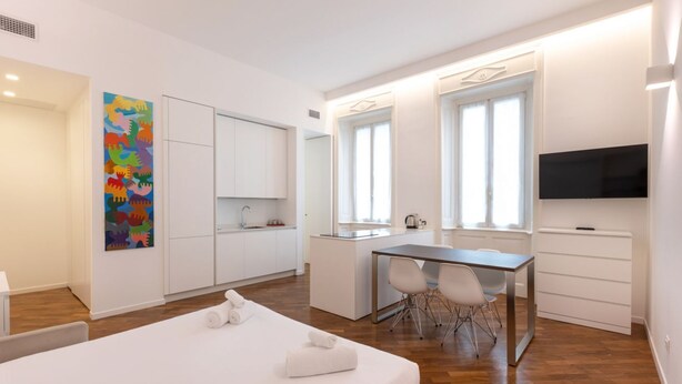 Una habitación de hotel moderna con una cama grande, un escritorio, una silla, un televisor y una obra de arte colorida en la pared.
