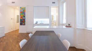 Una cocina moderna con armarios blancos, una isla central y un cuadro abstracto y colorido en la pared.