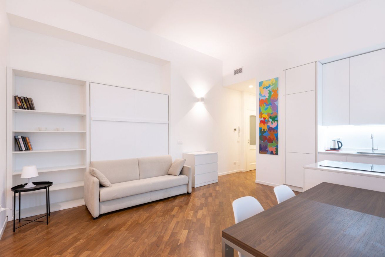 Ein moderner, minimalistischer Wohnraum mit Sofa, Esstisch und Küchenzeile.