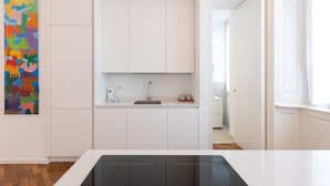 Una cocina moderna con armarios blancos, una estufa negra y una obra de arte colorida en la pared.